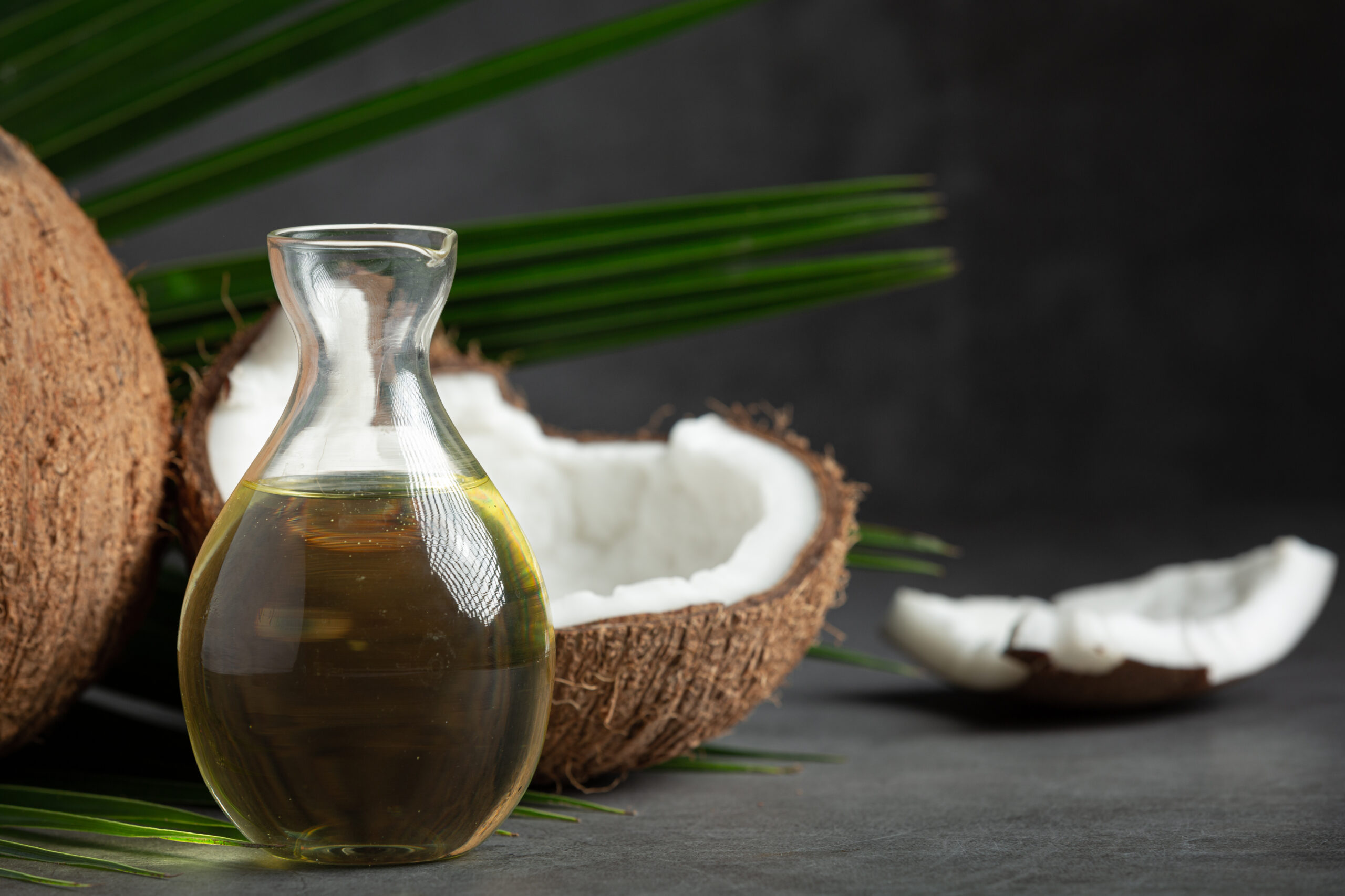 a jug of coconut oil whit coconut put on dark background